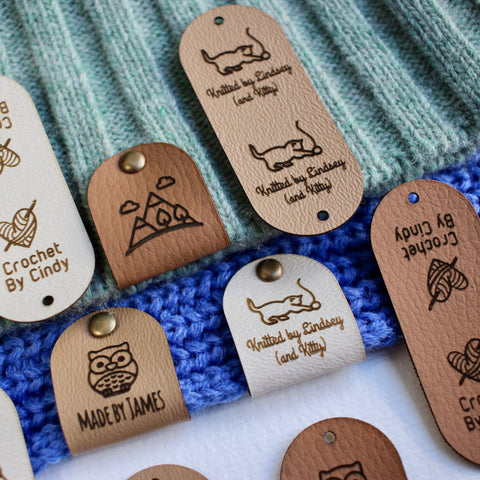 Multiple Faux leather tags with custom logos and text attached to knitted and crocheted fabrics